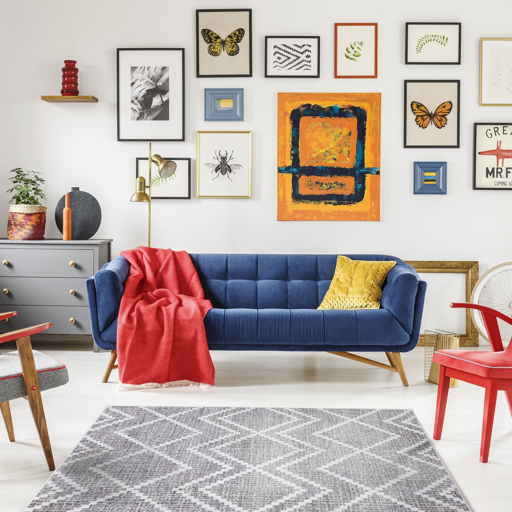 Zigzag patterned grey carpet in colorful living room interior with red armchair & navy sofa